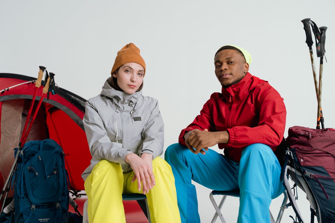 Two hikers in winter clothing ready for adventure with backpacks and tents.